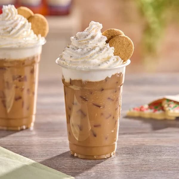 Vanilla cream cold brew in a clear cup beside a warm chai latte on a counter